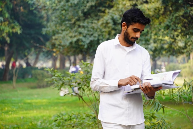 Indian boy with books pen and standing near college campus