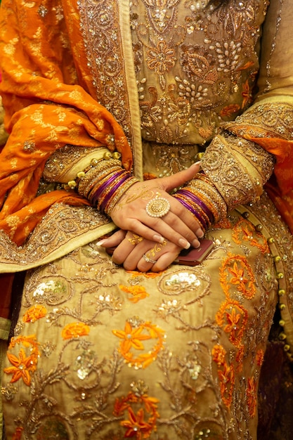 Indian bride outfit with golden henna jewelry and embroidery dress close up