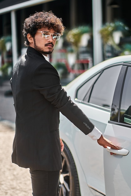 Indian businessman opens door in white car.