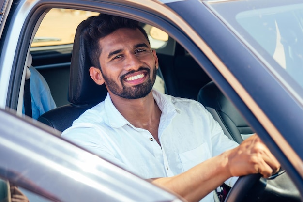 Indian businessman standing near car outdoors on sea beach summer good day.a man in a white shirt and snow-white smile rejoicing buying a new car enjoying a vacation by the ocean