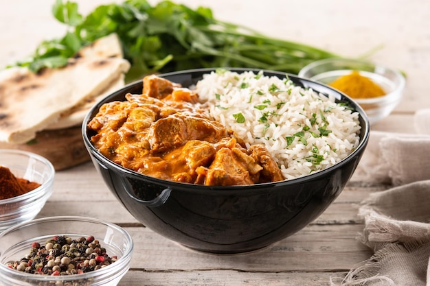 Indian butter chicken in black bowl on wooden table