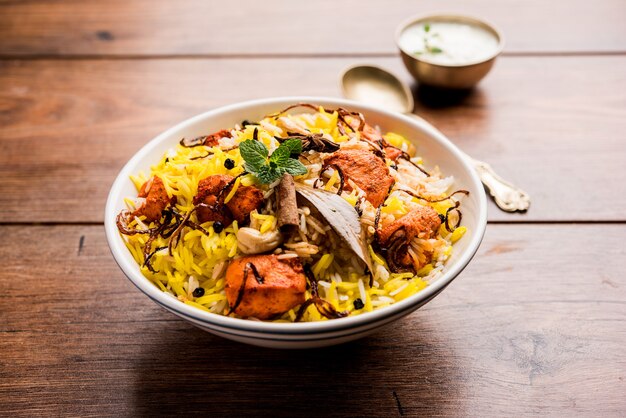 Indian Chicken Tikka Biriyani served in a bowl with yogurt. selective focus