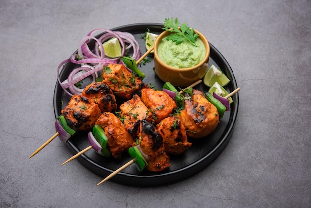 Indian chicken tikka kebabs, marinated in spices and yogurt and roasted in tandoor. served with green chutney and onion. selective focus