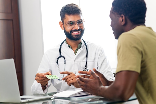 Indian doctor therapist in white coat consulting supporting patient in modern clinic hospital