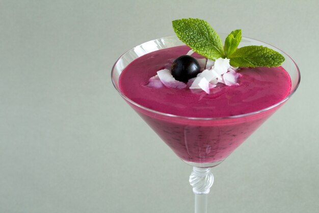 Indian drink lassi with black currant in the glass on grey