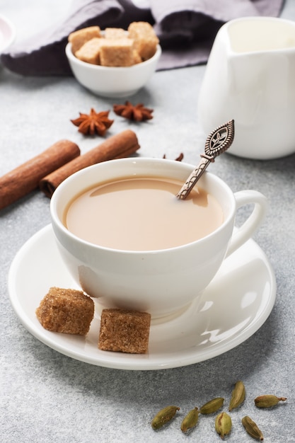 Indian drink masala tea with milk and spices. Cardamom sticks cinnamon star anise cane sugar.