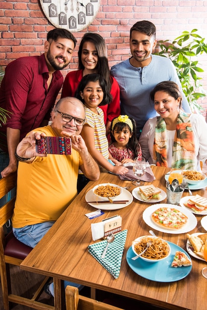 Indian Family eating food at dining table at home or restaurant having meal together