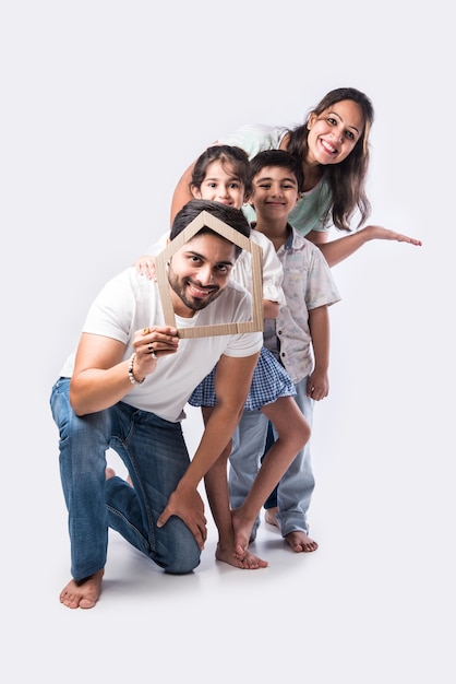 Indian family Father, mother, son and daughter holding 3D paper model of home - Real Istate Concept in India