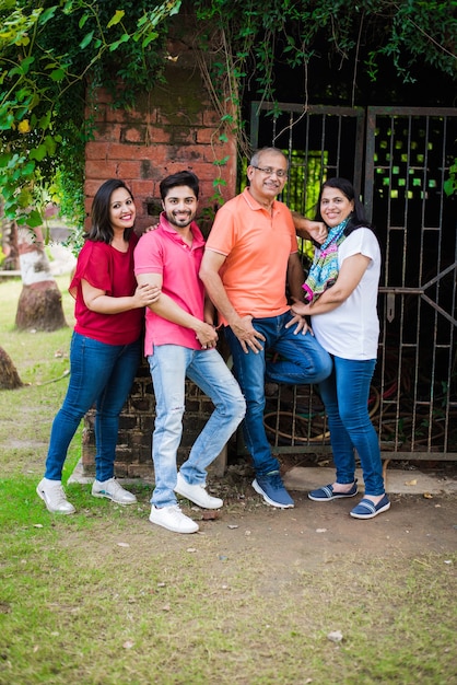 Indian family standing in line against wall covered with creepers. Multi generation of asian family in park or garden having fun, healthy family life concept