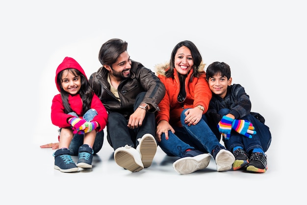 Indian family in warm clothes sitting against white background. Ready for winter