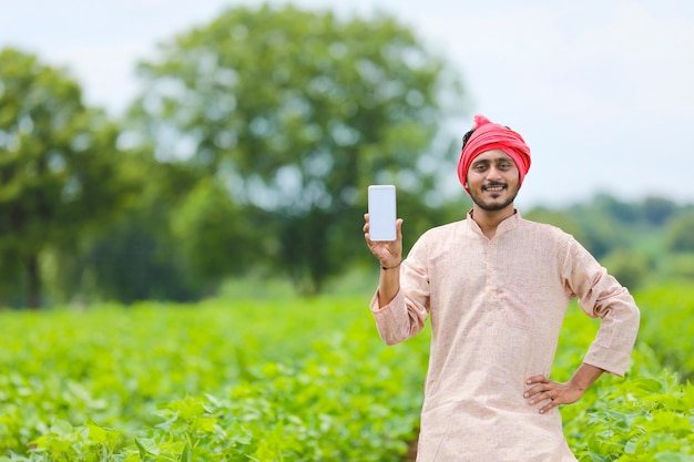 Indian farmer showing smartphone screen at agriculture field