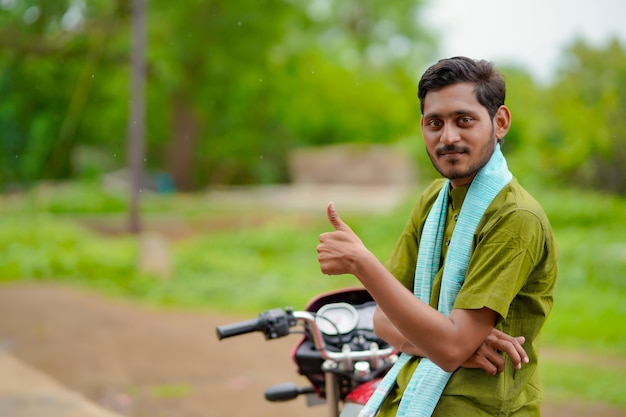 Indian farmer sitting on bike and showing thumps up