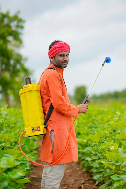 Indian farmer spraying pesticide at cotton field.