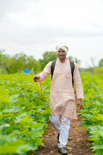 Indian farmer spraying pesticide at cotton field.