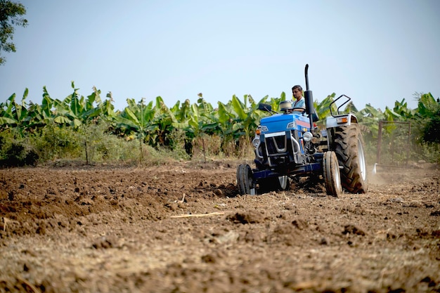 Indian farmer working with tractor in agriculture field.