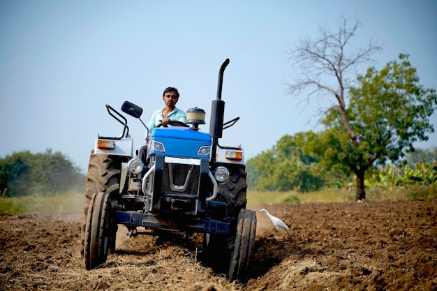 Indian farmer working with tractor in agriculture field.