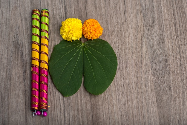 Indian Festival Dussehra and Navratriand marigold flowers with Dandiya sticks on a wooden background