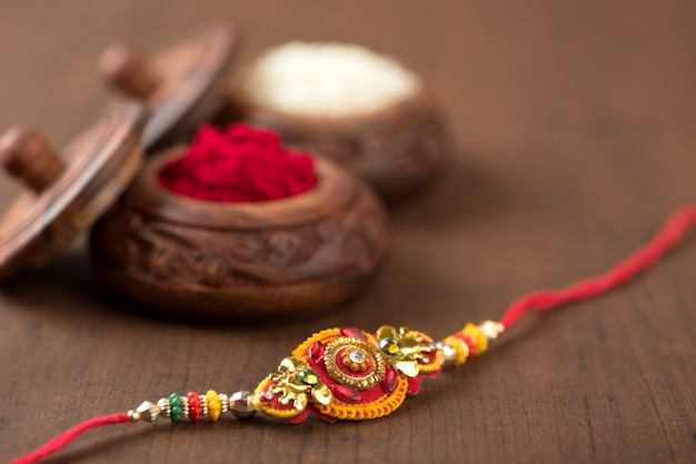 Indian festival: Raksha Bandhan background with an elegant Rakhi, Rice Grains and Kumkum