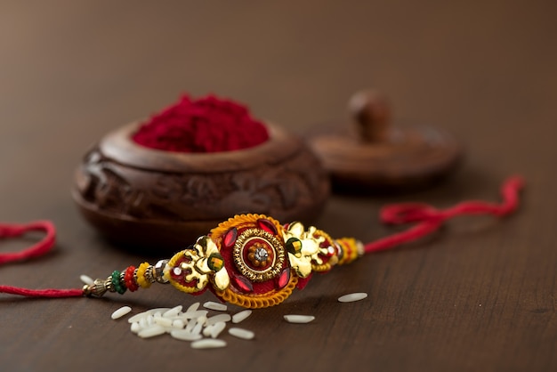 Indian festival: Raksha Bandhan background with an elegant Rakhi, Rice Grains and Kumkum