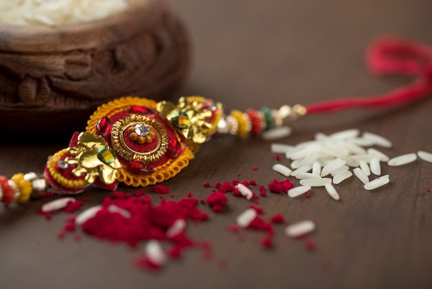 Indian festival: Raksha Bandhan background with an elegant Rakhi, Rice Grains and Kumkum