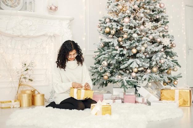 Indian girl in eyeglasses near Christmas tree holding a gift