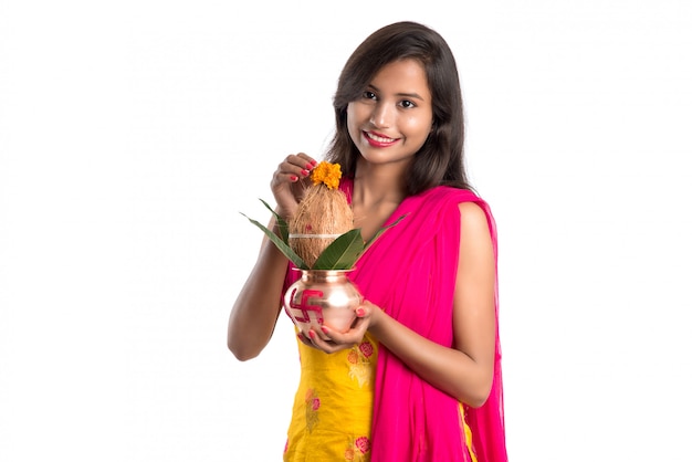 Indian girl holding a traditional copper Kalash, Indian Festival, copper Kalash with coconut and mango leaf with floral decoration, essential in Hindu Pooja.