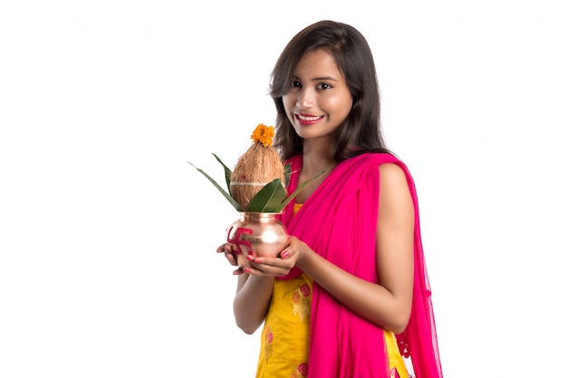 Indian girl holding a traditional copper Kalash, Indian Festival, copper Kalash with coconut and mango leaf with floral decoration, essential in Hindu Pooja.