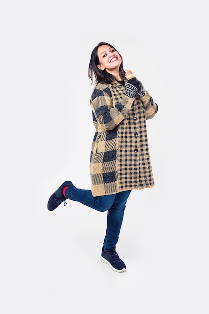 Indian girl or woman eating ice cream while wearing warm winter clothes on white background