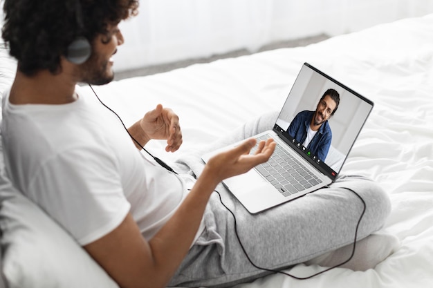 Indian guy having video call with his friend using laptop