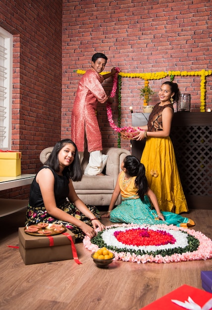 Indian Kids celebrating Diwali, Deepawali, Bhai Dooj or Rakhi or Raksha Bandhan with flower rangoli, gifts, diya