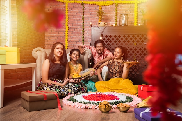 Indian Kids celebrating Diwali, Deepawali, Bhai Dooj or Rakhi or Raksha Bandhan with flower rangoli, gifts, diya