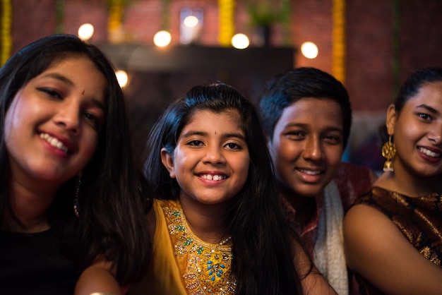 Indian Kids celebrating Diwali, Deepawali, Bhai Dooj or Rakhi or Raksha Bandhan with flower rangoli, gifts, diya