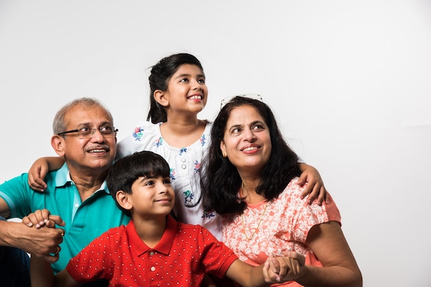 Indian Kids with grandparents smiling while sitting on a white background indoors, selective focus