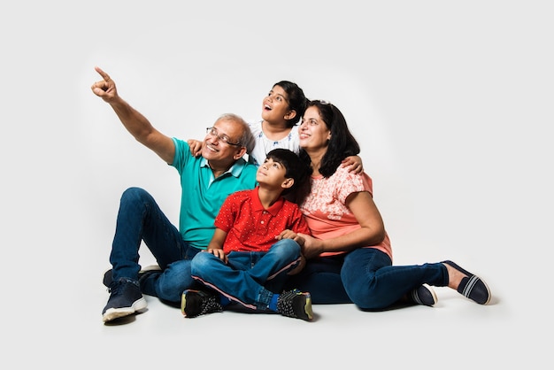 Indian Kids with grandparents smiling while sitting on a white background indoors, selective focus