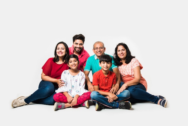 Indian Kids with parents and grandparents, sitting isolated over white background, studio shot