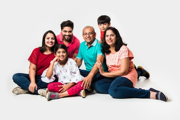 Indian Kids with parents and grandparents, sitting isolated over white background, studio shot