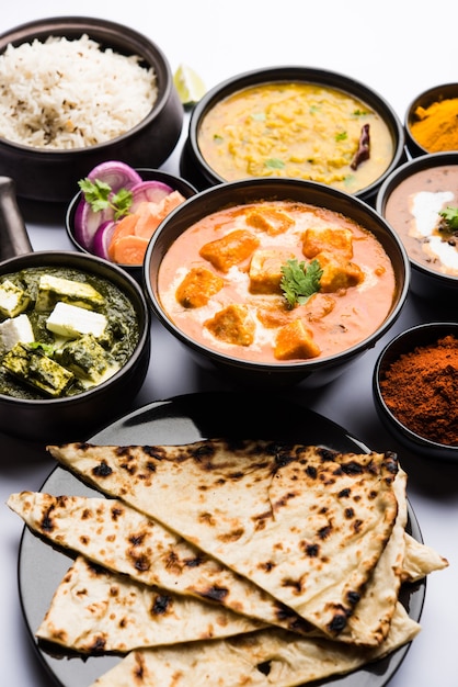 Indian Lunch or Dinner main course food in group includes Paneer Butter Masala, Dal Makhani, Palak Paneer, Roti, Rice etc, Selective focus