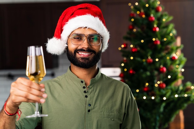 Indian man drinking alcohol at home Christmas tree lights garland background