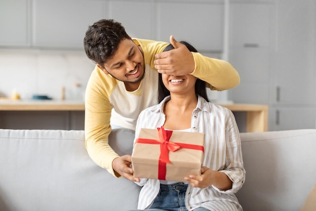 Indian man giving gift to woman on couch