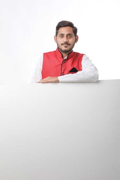 Indian man holding white board, promoting offers on festival season while wearing traditional cloths, standing over white background.