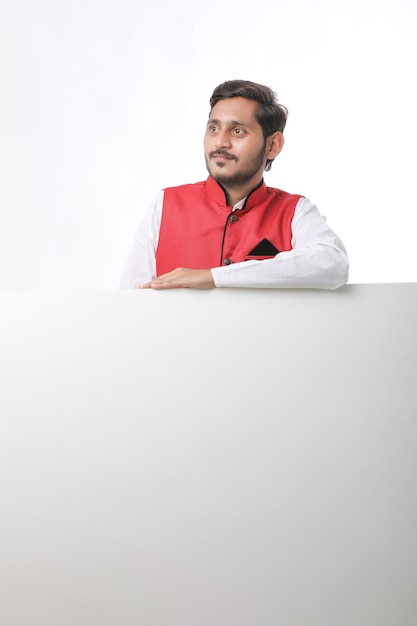 Indian man holding white board, promoting offers on festival season while wearing traditional cloths, standing over white background.