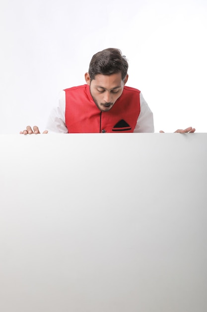 Indian man holding white board, promoting offers on festival season while wearing traditional cloths, standing over white background.