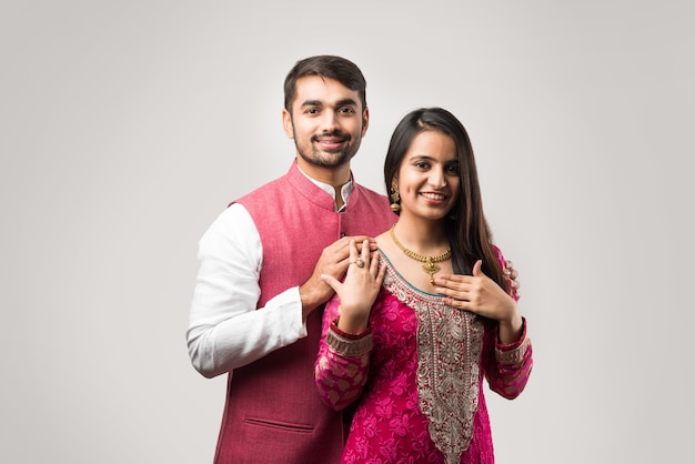 Indian man tying or presenting gold necklace to his beautiful wife on birthday, valentine's day, anniversary or Diwali festival