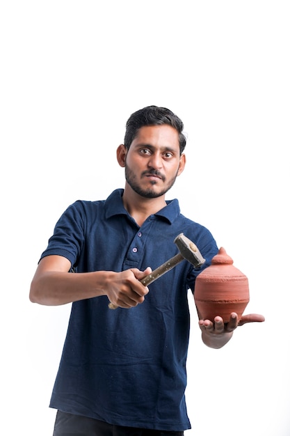 Indian man using hammer for broken clay piggy bank.