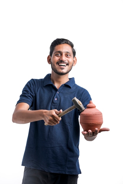 Indian man using hammer for broken clay piggy bank.