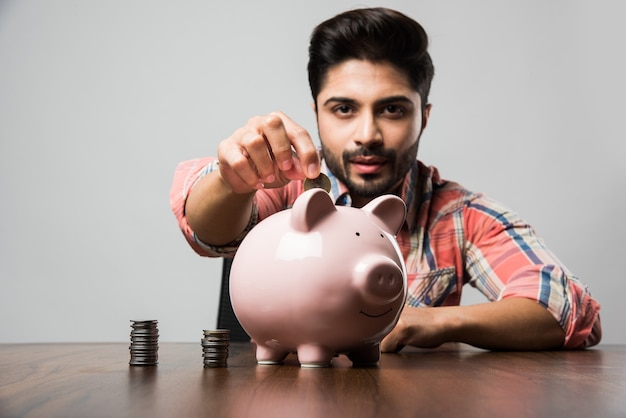 Indian Man with Piggy Bank, sitting at table