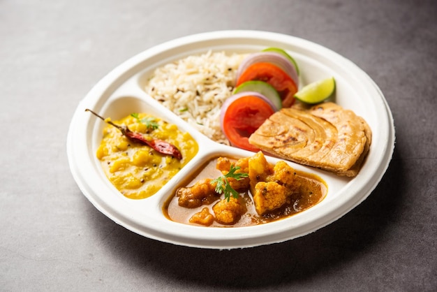 Indian mini meal parcel platter or combo thali with Gobi Masala roti dal tarka jeera rice salad