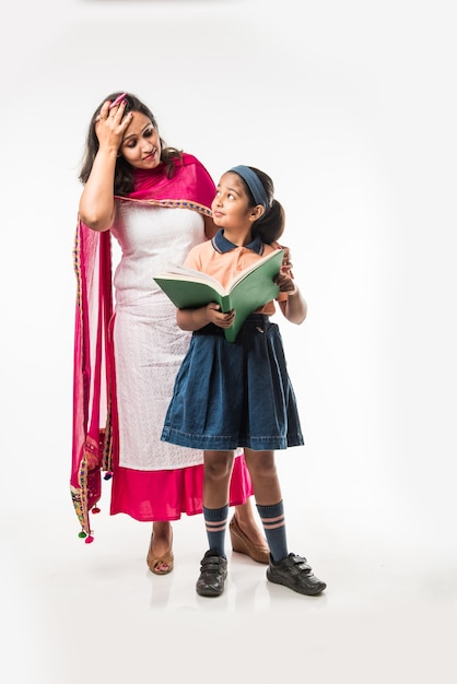 Indian Mother helping school girl with uniform getting ready with Lunch Box, hair style or waiting for school bus