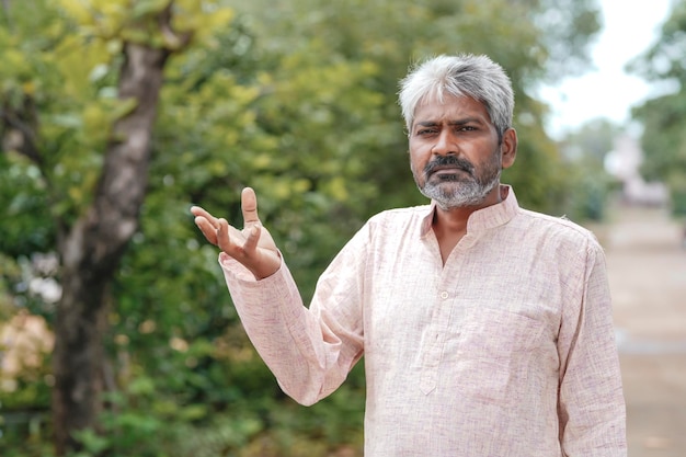 Indian old man giving expression on nature background