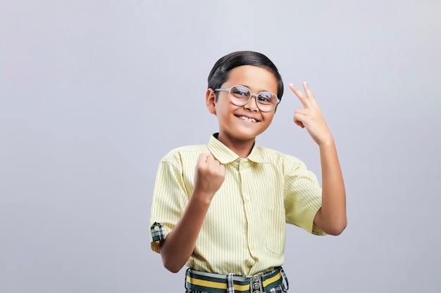 Indian school boy giving winning gesture on white background